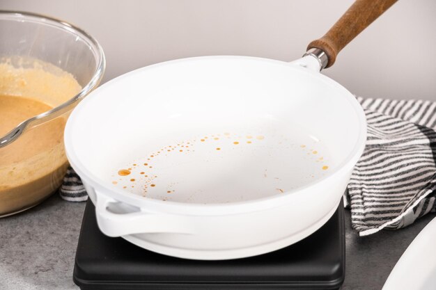 Frying pumpkin pancakes batter on a white frying pan