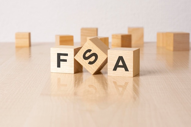 FSA an abbreviation of wooden blocks with letters on a gray background reflection caption on the mirrored surface of the table selective focus