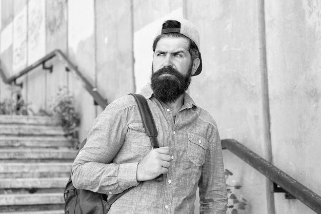 Fuel your soul with travel Confident man walk street Male barber care brutal hipster with travel backpack hiking adventure concept urban style Mature hipster with beard traveller Bearded man