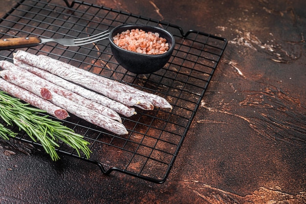 Fuet Catalan dry sausages with rosemary Dark background Top view Copy space