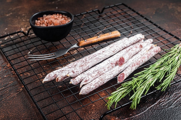 Fuet Catalan dry sausages with rosemary Dark background Top view