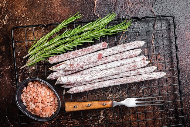 Fuet Catalan dry sausages with rosemary Dark background Top view