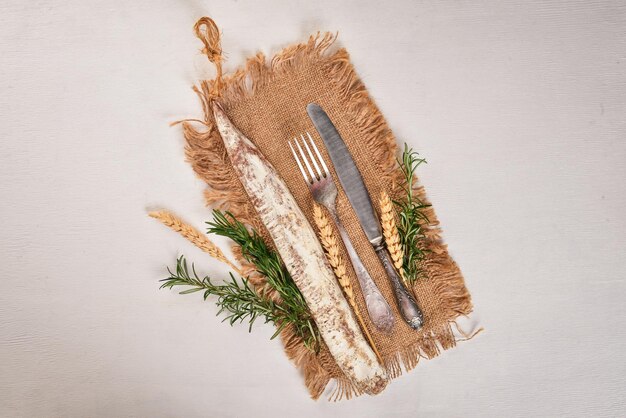 Fuet Salami and Rosemary Traditional Spanish sausage On a white wooden background Top view