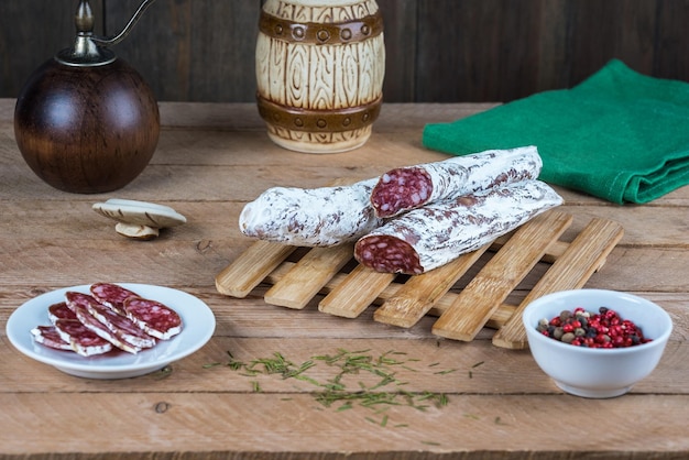 Fuet sausage with a noble mold cut in slices with spices on a rustic wooden table