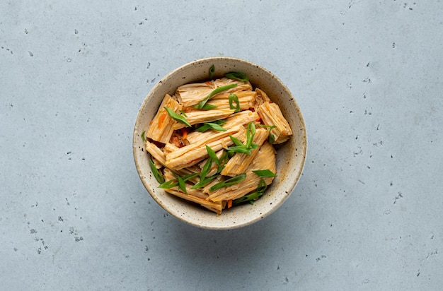 Fuju salad with carrots in a ceramic bowl, top view