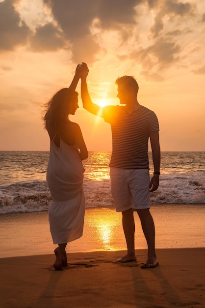 Full body adult lovely family couple dancing at ocean sunset background man and woman in casual clothes walking together sandy beach outdoor