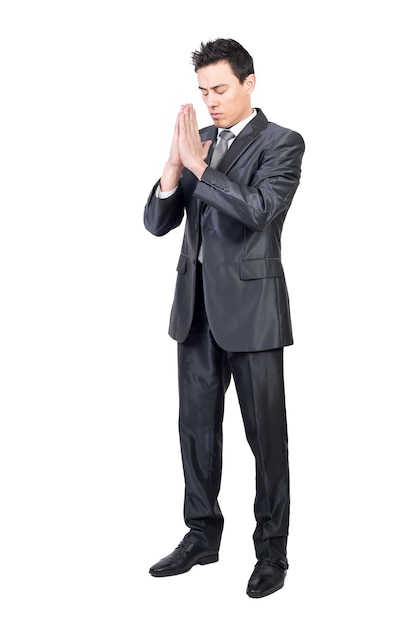 Full body of hoping peaceful male worker in classy suit standing with prayer hands in studio against white background