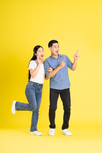 Full body image of asian couple posing on yellow background