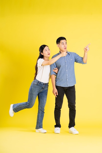 Full body image of asian couple posing on yellow background