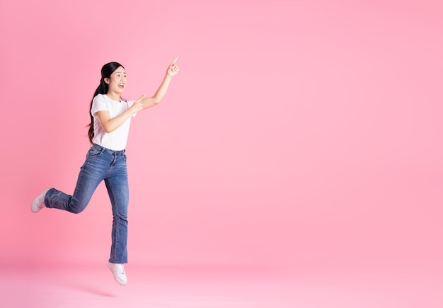 Full body image of Asian girl posing on pink background