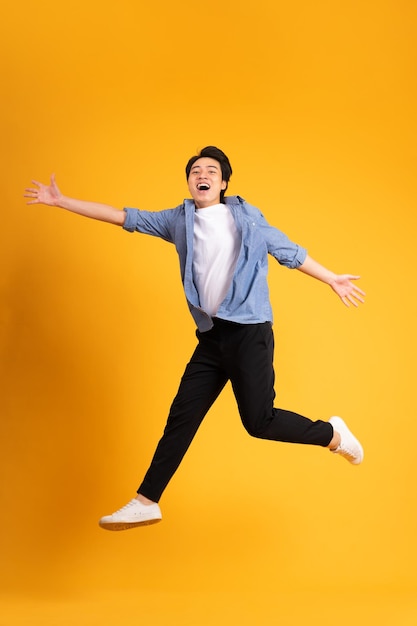 Full body image of asian man posing on yellow background