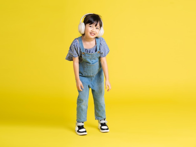 Full body image of beautiful asian baby girl on yellow background