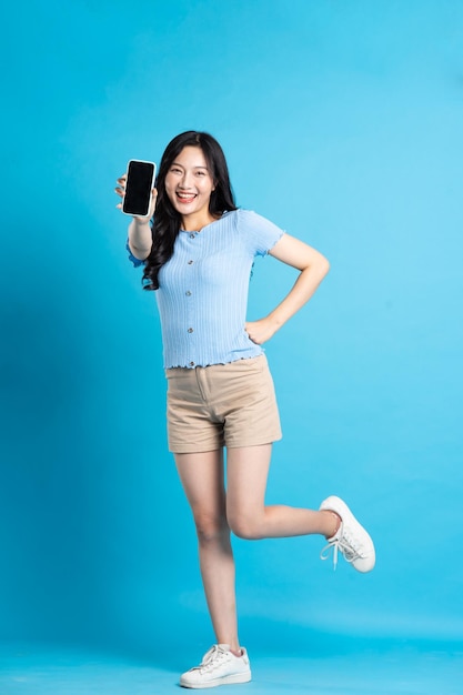 Full body image of beautiful asian girl posing on blue background