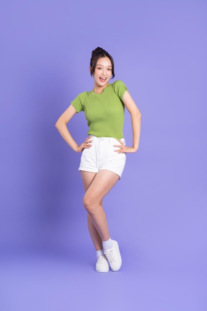 full body image of beautiful asian girl posing on pink background