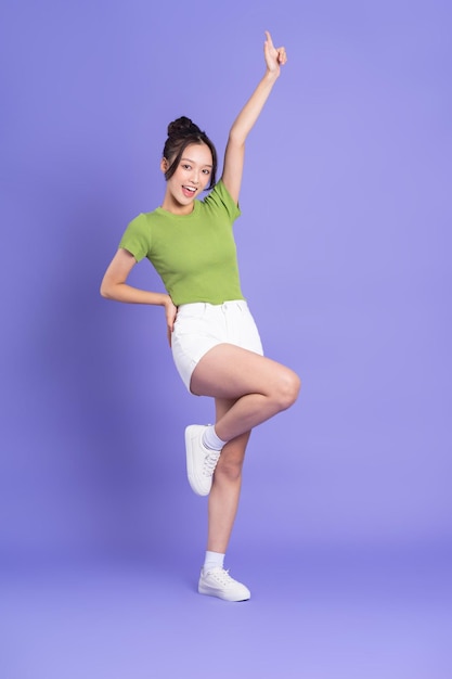 Full body image of beautiful asian girl posing on pink background