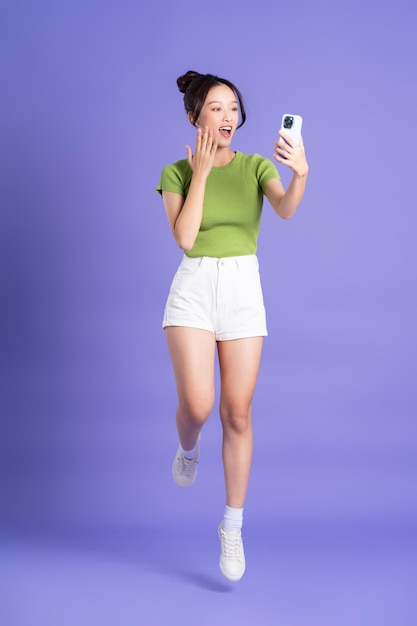 Full body image of beautiful asian girl posing on pink background