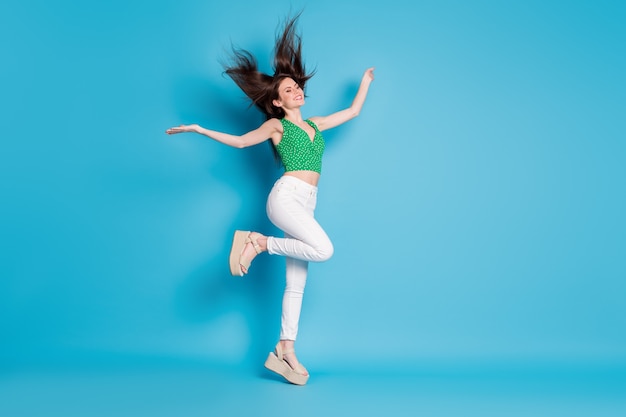 Full body photo of candid content charming  girl jump enjoy rejoice air fly haircut blow hold hands raise wear good look outfit shoes isolated over blue color background