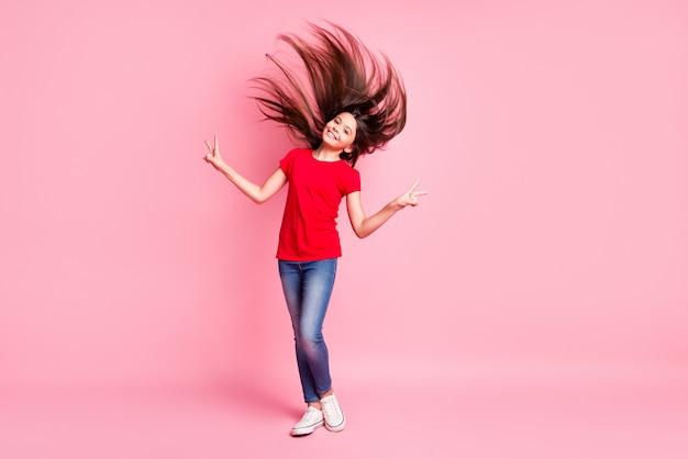 Full body photo of latin kid girl with flying hair make v-sign wear casual style outfit isolated over pastel color background