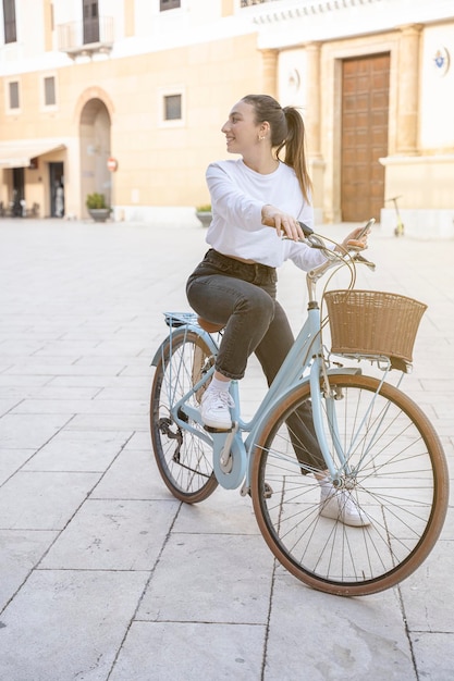 Full body portrait of a beautiful young woman casual dressed with retro bicycle outdoors in a square