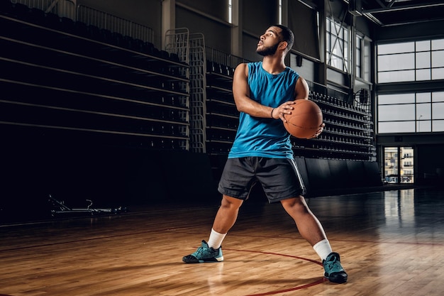 Full body portrait of Black professional basketball player in an action in basketball field.