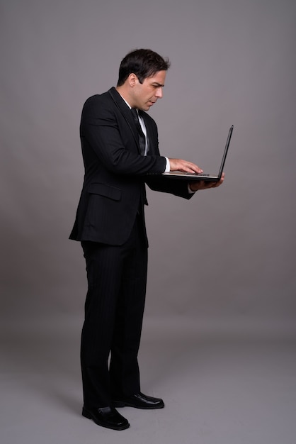 Full body shot of handsome Persian businessman with laptop