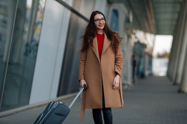 Full body side portrait of business woman walking with suitcase in terminal