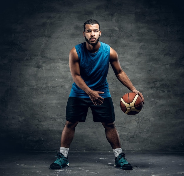 Full body studio portrait of a black basketball player playing with a ball.