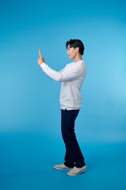 full body young man doing selfie shot on mobile cell phone isolated on blue background