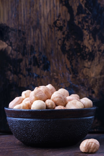 Full bowl of hazelnuts on table with copy space on wooden backgrounds