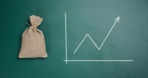 A full canvas bag and a graph drawn in chalk on a green board Growth of incomes receipt of subsidies increase in income