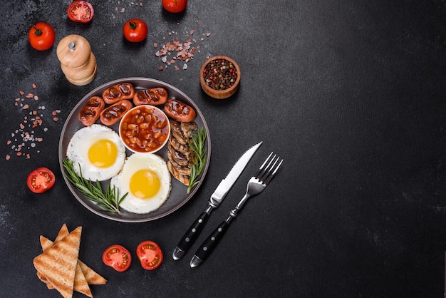 Full english breakfast bean fried eggs roasted sausages tomatoes mushrooms on a dark concrete table with toasted bread