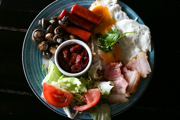 Full English breakfast with fried eggs on wood