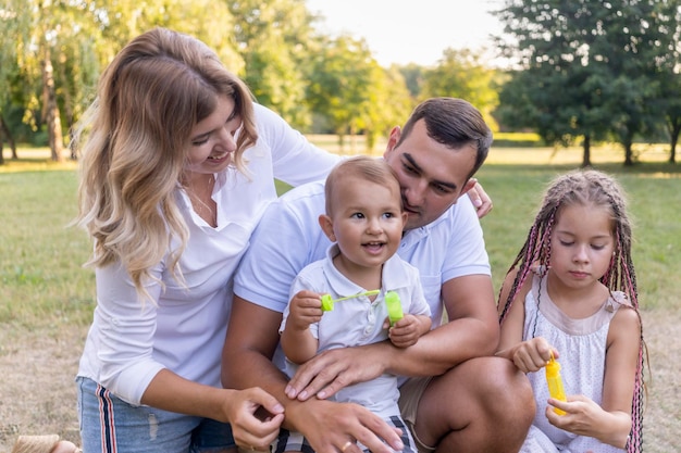 Full family with son and daughter relax in park at sunset with rays of sun in summer and they launch