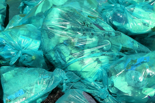 Full frame background of turquoise plastic trash bags with generic domestic waste