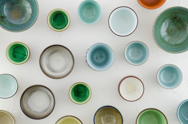 Full frame of ceramic and glass bowls and tea cups on white background