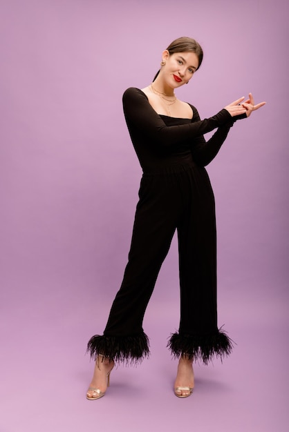 In full growth beautiful young caucasian brunette girl with collected hair in black elegant suit in studio Lifestyle concept