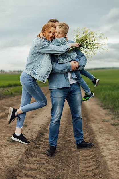 Full growth shot young family in denim casual clothes walking around the park holding hands on warm spring day