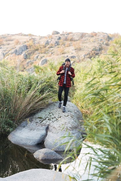 Full lengh of a happy fit man carrying backpack hiking at the forest