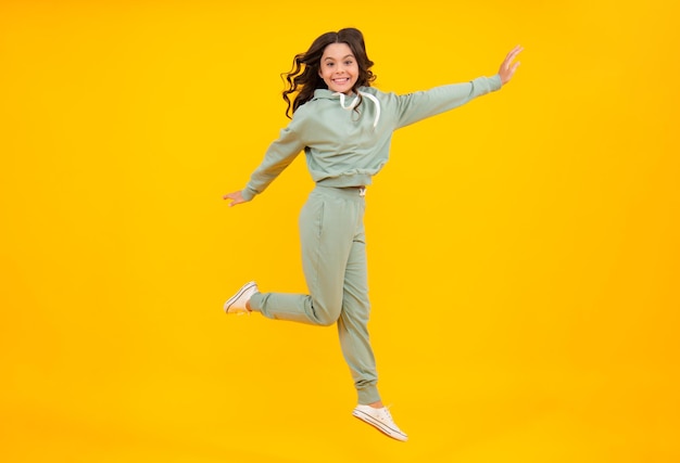 Full length of attractive cheerful girl in sport wear isolated over yellow background Sportwear for teenager child