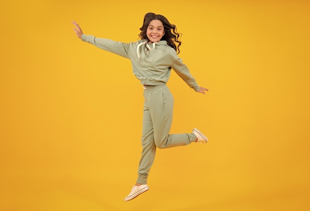 Full length of attractive cheerful girl in sport wear isolated over yellow background Sportwear for teenager child