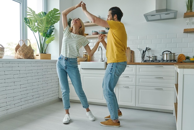 Full length of beautiful young couple dancing at the domestic kitchen