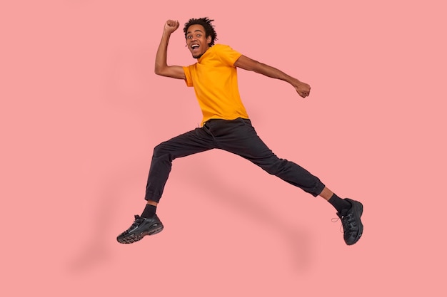 Full length body profile side photo of positive cheerful funky black guy hear about wonderful black Friday sales jump run want be first wear casual style outfit isolated over a pink background.