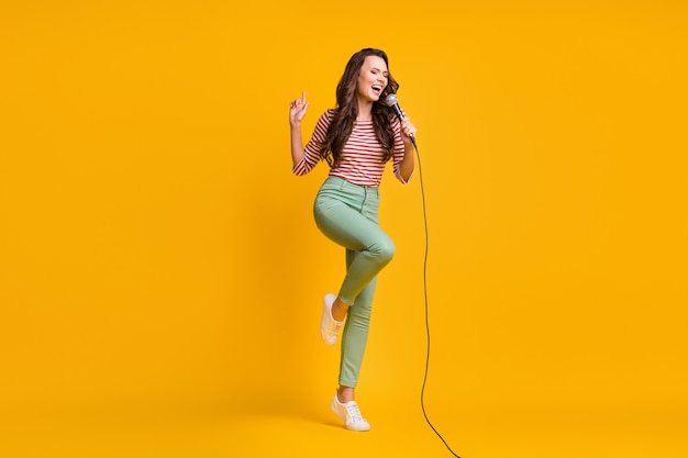 Full length body size photo of girl singing song with microphone in karaoke isolated on bright yellow color background