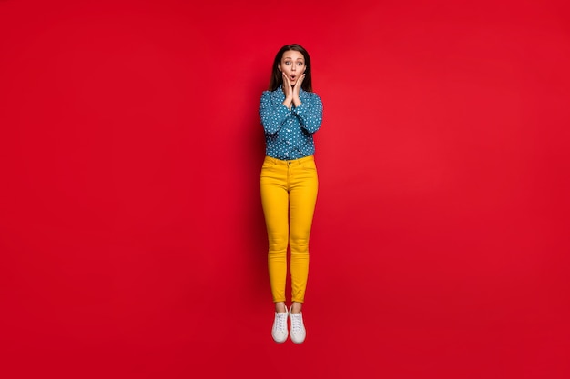 Full length body size view of lovely amazed cheery girl jumping news reaction pout lips isolated over bright red color background