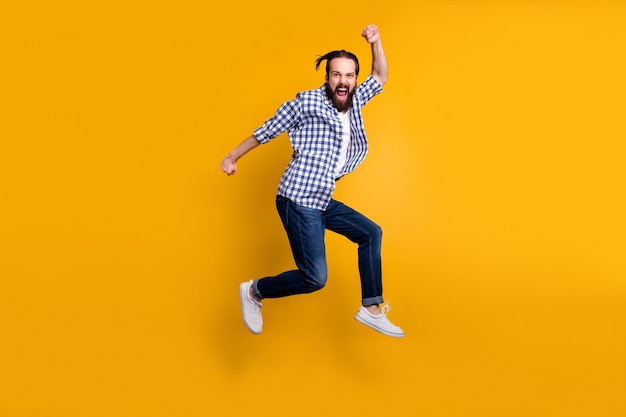 Full length body size view of nice funky crazy overjoyed cheerful bearded guy in checked shirt jumping up