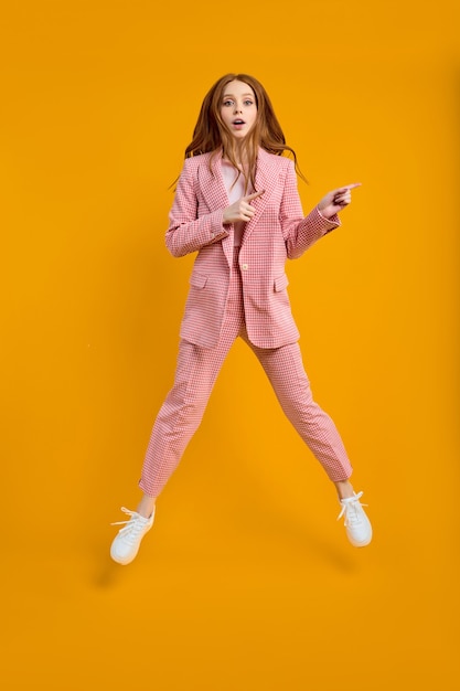 Full length body size view of nice wondered business lady in suit in shock, emotional woman with red hair jumping omg expression isolated over bright vivid shine vibrant yellow color background