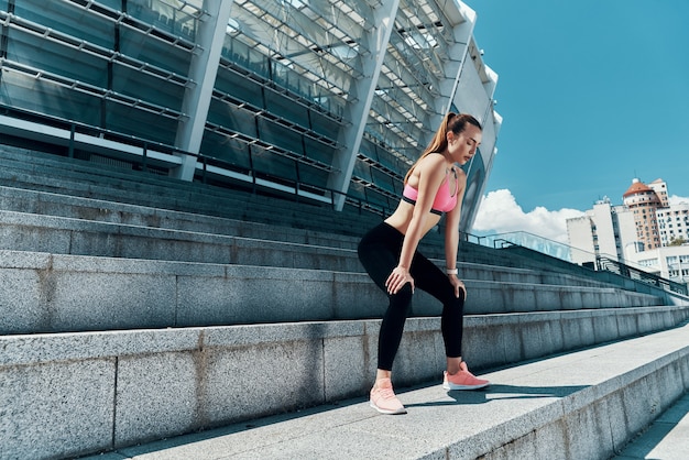 Full length of confident young woman in sports clothing standing outdoors