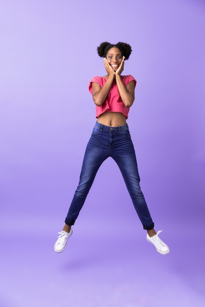 Full length excited african american woman smiling and jumping, isolated