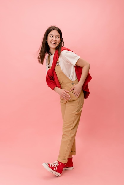 Full length fashionable caucasian young brunette woman wears casual clothes looking away on pink background People sincere emotions lifestyle concept