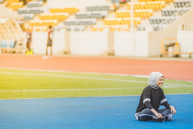 Photo full length of female athlete sitting at stadium